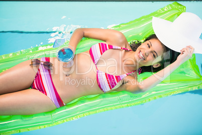 Happy woman relaxing on air bed in swimming pool