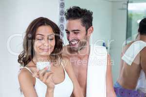 Woman looking at cream while husband smiling beside her