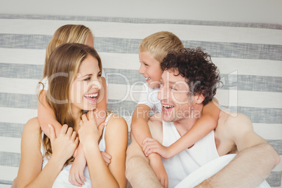 Joyful family playing together on bed