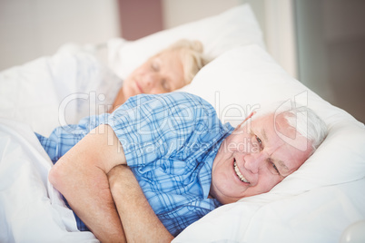 Portrait of man lying with wife on bed