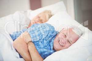 Portrait of man lying with wife on bed