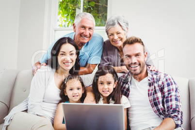 Portrait of smiling multi generation family using laptop