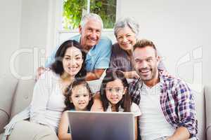 Portrait of smiling multi generation family using laptop