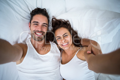 High angle view of couple taking self portrait on bed