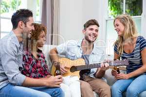 Man playing guitar while friends enjoying beer