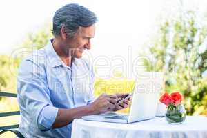 Casual businessman using laptop and smartphone