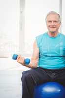 Portrait of senior man holding dumbbell