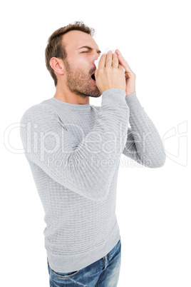 Young man holding a tissue and sneezing