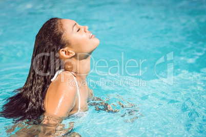 Beautiful woman in white bikini relaxing in swimming pool