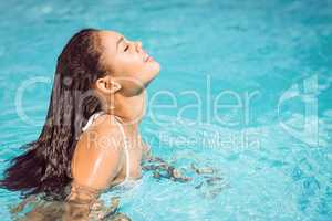 Beautiful woman in white bikini relaxing in swimming pool