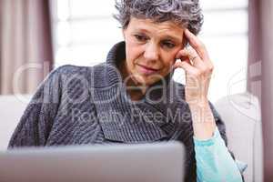 Mature woman thinking while using laptop