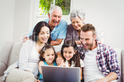 Smiling multi generation family using laptop