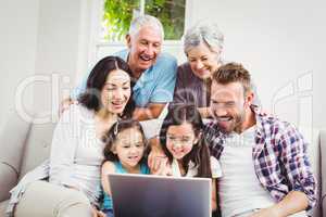 Smiling multi generation family using laptop