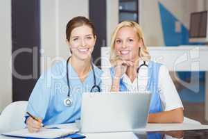 Portrait of smiling female doctors sitting at desk