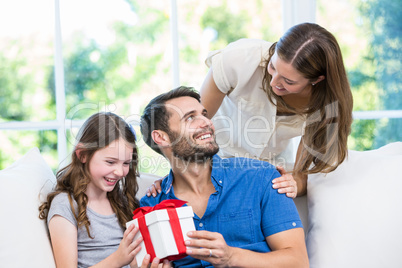 Man looking at wife while holding gift with daughter