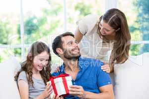 Man looking at wife while holding gift with daughter