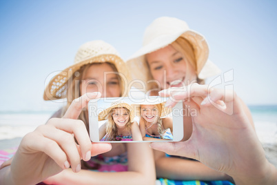 Two friends taking selfie while lying on the beach