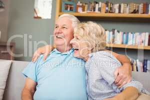 Senior couple laughing while sitting on sofa