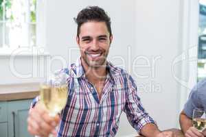 Handsome young man showing wineglass while sitting