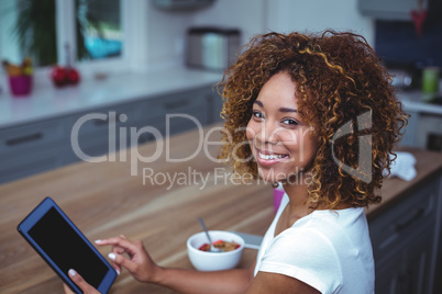 Young woman using digital tablet while sitting by table