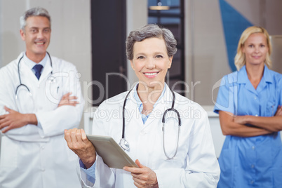 Cheerful doctor holding digital tablet while colleagues with arm
