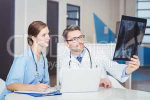 Doctor examining X-ray with colleague sitting at desk