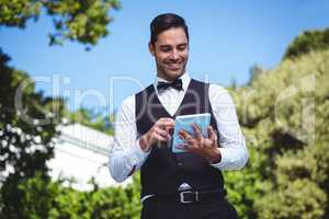 Handsome waiter using tablet computer