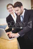 Business people using laptop by counter