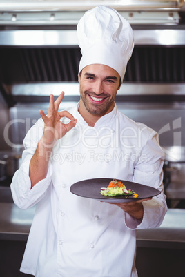 Male chef holding plate and doing ok sign