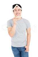 Young man holding house shaped popsicle sticks on face