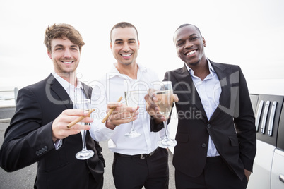 Well dressed men drinking champagne next to a limousine