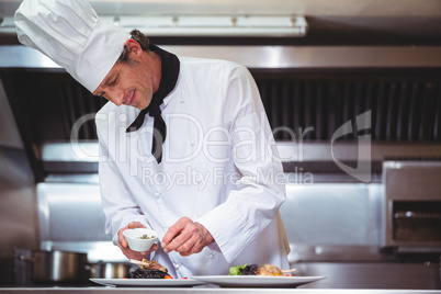 Chef sprinkling spices on dish