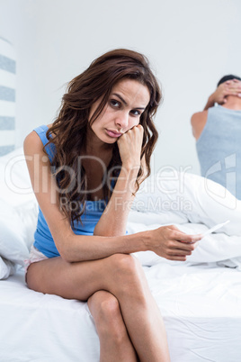 Portrait of serious woman sitting on bed