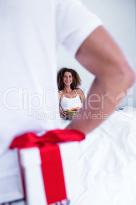 Man hiding gift behind his back for wife