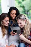 Happy young female friends looking in mobile phone