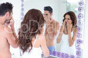 Couple cleaning face while looking in mirror