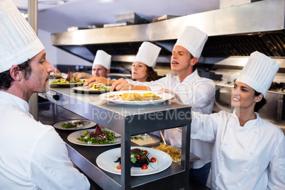 Chefs handing dinner plates through order station