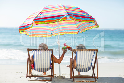 Cute mature couple lying on deckchairs