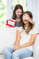 Daughter covering eyes of mother for surprise gift