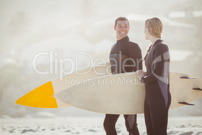 Couple with surfboard standing on the beach