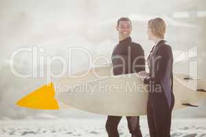 Couple with surfboard standing on the beach