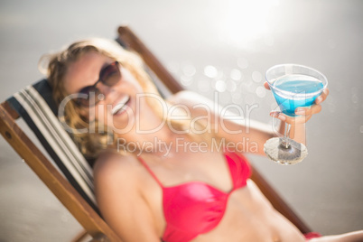 Young woman sitting on armchair with cocktail drink