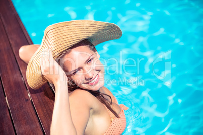 Portrait of woman wearing straw hat leaning on wooden deck by po