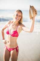 Portrait of woman in bikini holding a hat on beach