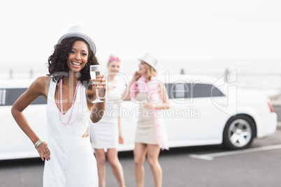 Frivolous women drinking champagne next to a limousine