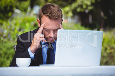 Businessman using laptop having a headache