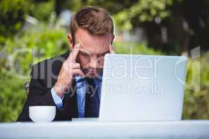 Businessman using laptop having a headache