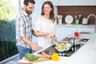 Man helping woman in cooking food