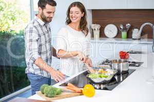 Man helping woman in cooking food