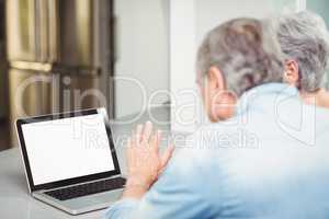 Senior couple using laptop at table